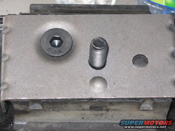 Close-up of a metal motor mount with a hex bolt and threaded stud