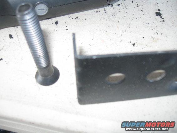 Close-up of a bolt and a black metal bracket with two holes