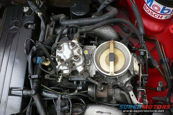 Engine bay of a 1986 Mercedes-Benz E-Class, showing the throttle body and fuel injection system