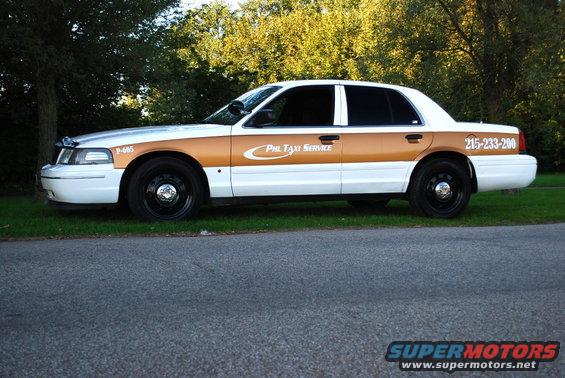 Side view of a 1998 Ford Crown Victoria taxi with gold stripe and "Phil Taxi Service" text