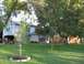 1983 Ford 427 - A suburban home with a large green lawn and mature trees. A vehicle is parked in the open garage.