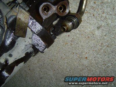 Close-up of a greasy steering gear box part with metal tubing