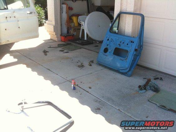 Blue Ford F-Series truck door removed and lying on concrete driveway