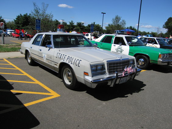 White police car with "STATE POLICE" text and "RHODE ISLAND STATE POLICE" on the door