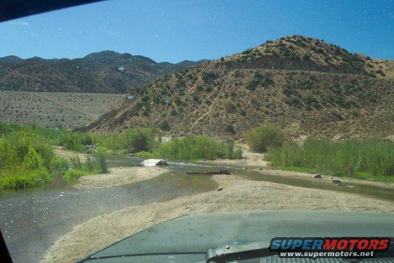 1995 Ford Bronco driving through shallow water in a desert landscape