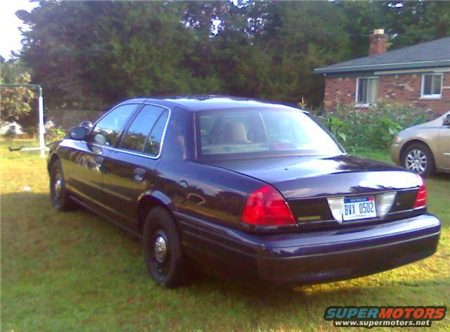 Dark blue 2003 Ford Crown Victoria sedan parked on grass, BVX 0502 license plate visible