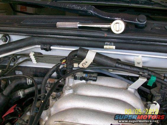 Ratchet on top of engine components, hoses, and wires. Date stamp 09/05/2002