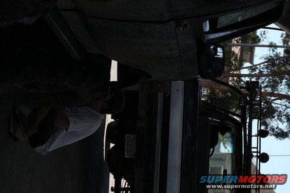 Underside of a vehicle with a person working on it, license plate visible