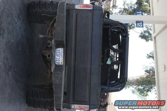 Rear view of a dark-colored SUV with large tires and a roll cage visible inside. California license plate reads 3SSF319