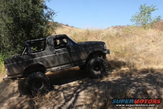 Dark gray Ford Bronco with large off-road tires on a dirt trail