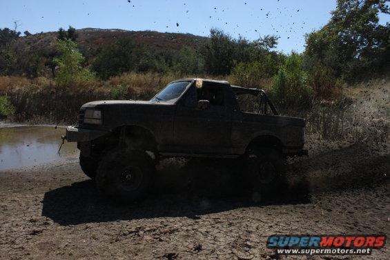1992 Ford Bronco driving through mud, side view