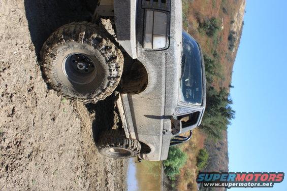 1992 Ford Bronco 3q-front view, covered in mud, on a dirt trail