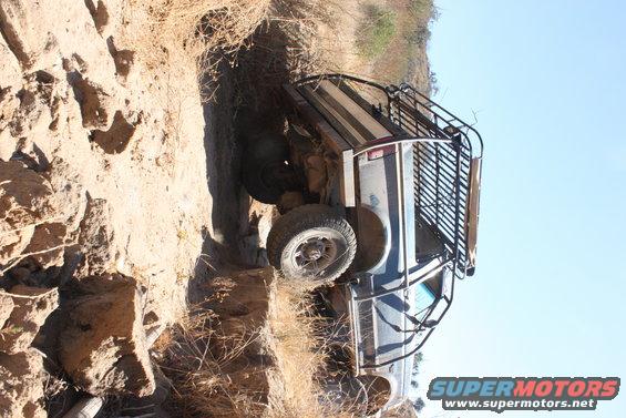 Off-road vehicle tilted on its side in a ditch with a rack on top