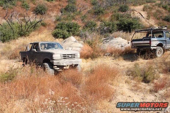 1992 Ford Bronco parked on dirt trail, another truck with roof rack behind it