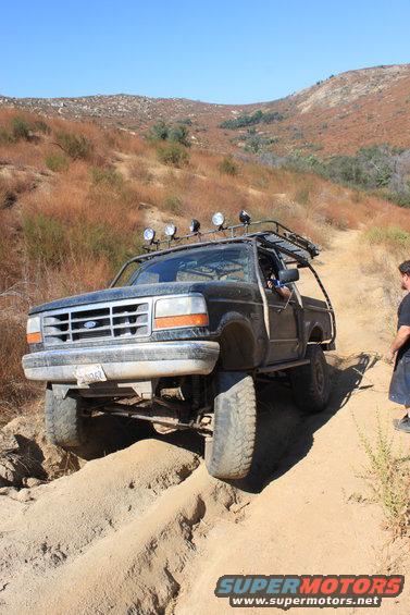 1992 Ford Bronco off-roading on a sandy trail, front 3/4 view