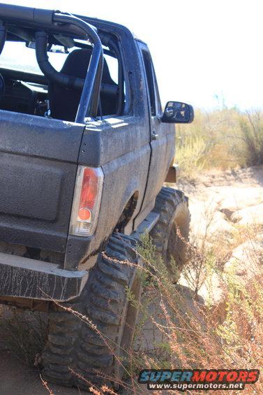 1992 Ford Bronco with roll cage and large tires on a dirt trail