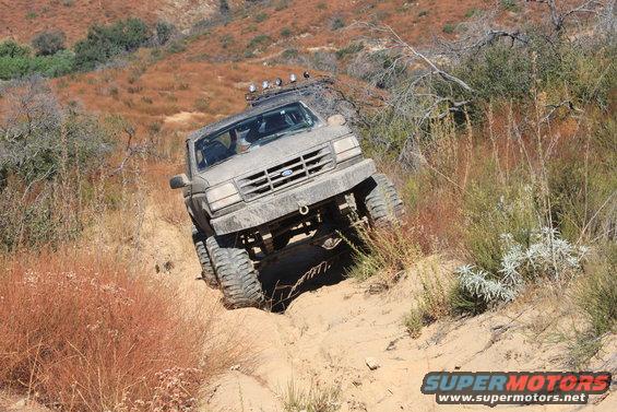 Gray 1992 Ford Bronco climbing a sandy hill with large tires