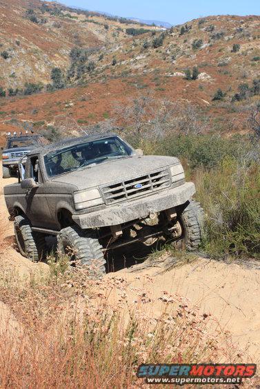 Muddy Ford F-Series truck on a dirt trail, another truck behind it