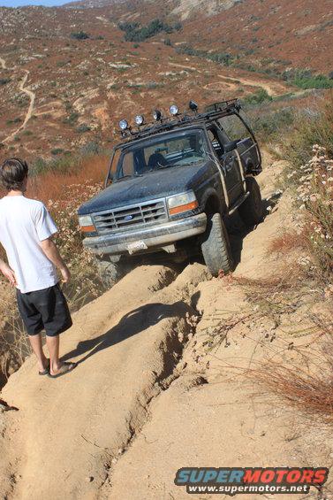 1992 Ford Bronco on a steep dirt trail with a person watching