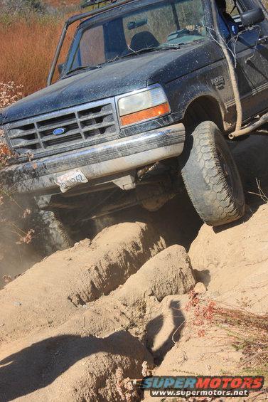 1992 Ford Bronco climbing over dirt obstacles on a trail