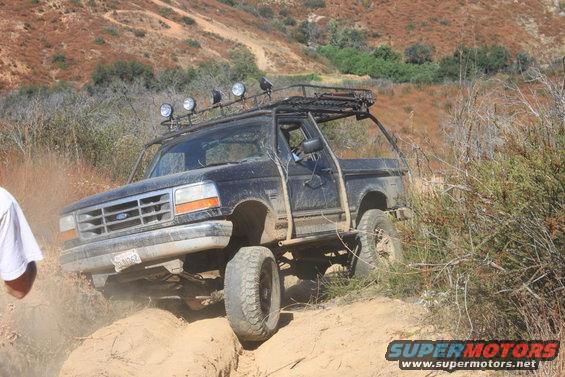 1992 Ford Bronco off-roading on a dusty trail with a roof rack
