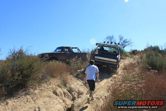 1992 Ford Bronco and another SUV on a dirt trail with a person walking