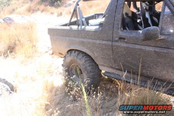 Mud-covered 1992 Ford Bronco side view, off-road tires, roll cage, racing seats