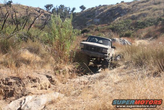 Gray 1992 Ford F-150 pickup truck off-roading on a dry, rocky trail