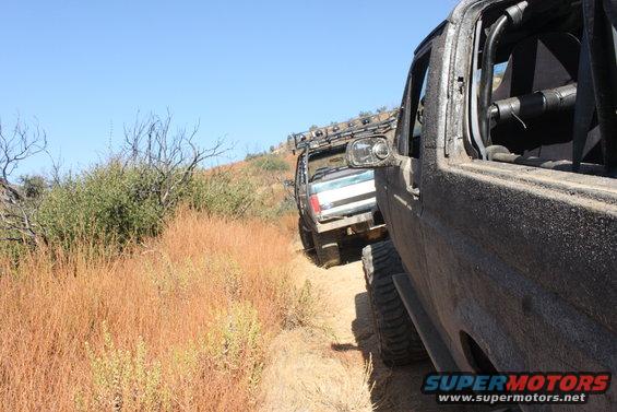 1992 Ford Bronco and another off-road vehicle on a dry, grassy trail