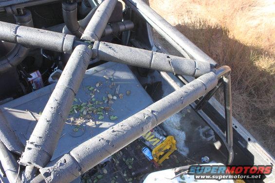 Interior roll cage with padding, debris on the floor, and a yellow tool organizer