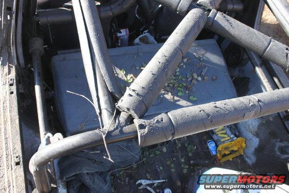 Interior of a vehicle with a roll cage, cooler, and some tools on the floor
