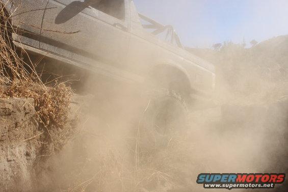 1992 Ford Bronco kicking up dust while driving off-road