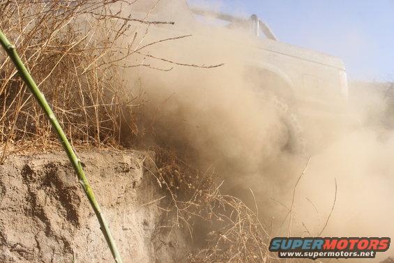 Truck driving off-road, kicking up a lot of dust