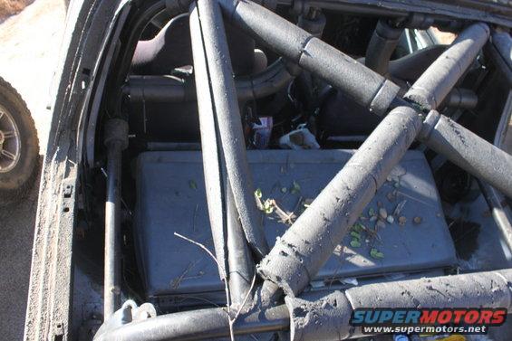 Vehicle interior with roll cage, debris on floor, and a tire visible