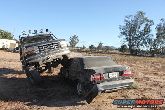 1992 Ford F-Series truck on a wrecked Volvo sedan in a dirt lot