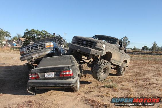Lifted 1992 Ford Bronco crushing a black sedan