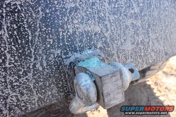 Close-up of a dirty vehicle's tow hitch with broken glass fragments