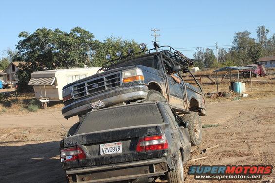 1992 Ford Bronco on top of a black Volvo sedan, front 3/4 view