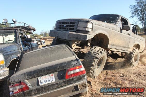 1992 Ford Bronco crushing a Volvo sedan on a dirt trail