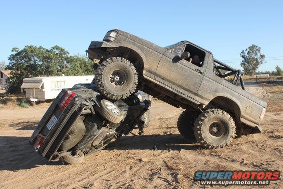 Muddy off-road truck on top of a flipped car