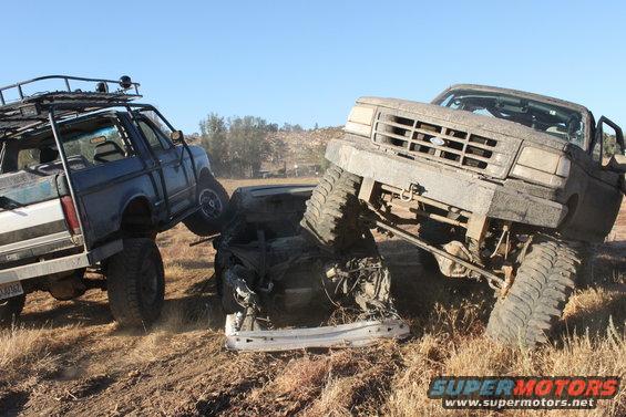 Front view of a wrecked Ford truck on top of another crushed vehicle