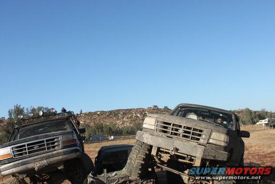 1992 Ford Bronco and another off-road truck stuck in mud