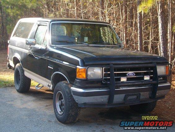 Black Ford Bronco with tan stripe, bull bar, and off-road tires parked outdoors