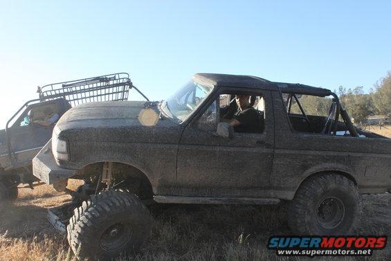 1992 Ford Bronco side view, mud-covered with roll cage and roof rack
