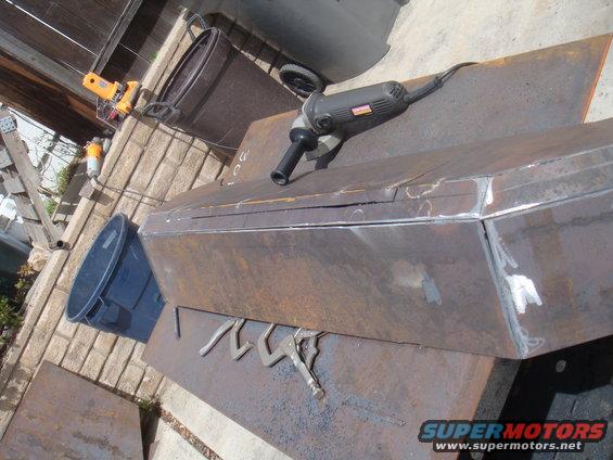 Metal fabrication project with angle grinder and clamps on workbench