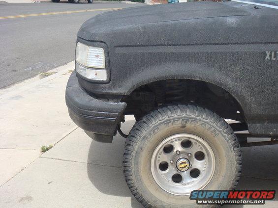 Front corner of black Ford F-Series truck, showing headlight, fender, and tire. XLT trim visible