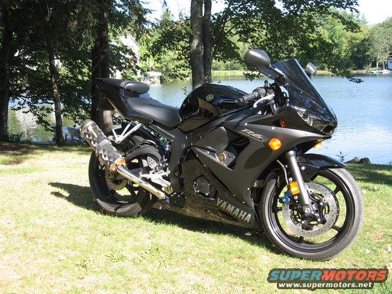 Black Yamaha R6 motorcycle parked on grass near a lake. "YAMAHA" visible on fairing