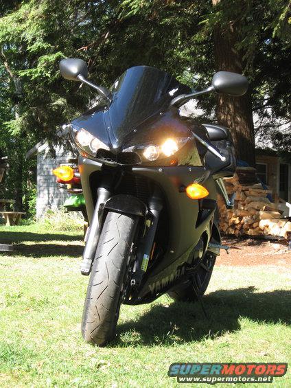 Black Yamaha motorcycle parked on grass, front view, with headlights on