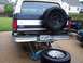 1992 Ford Bronco - The rear of a Ford Bronco is shown with a spare tire, a flat tire, and a jack underneath.