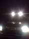 1992 Ford Bronco - The front grille of a 1992 Ford Bronco is visible at night, illuminated by its bright headlights.